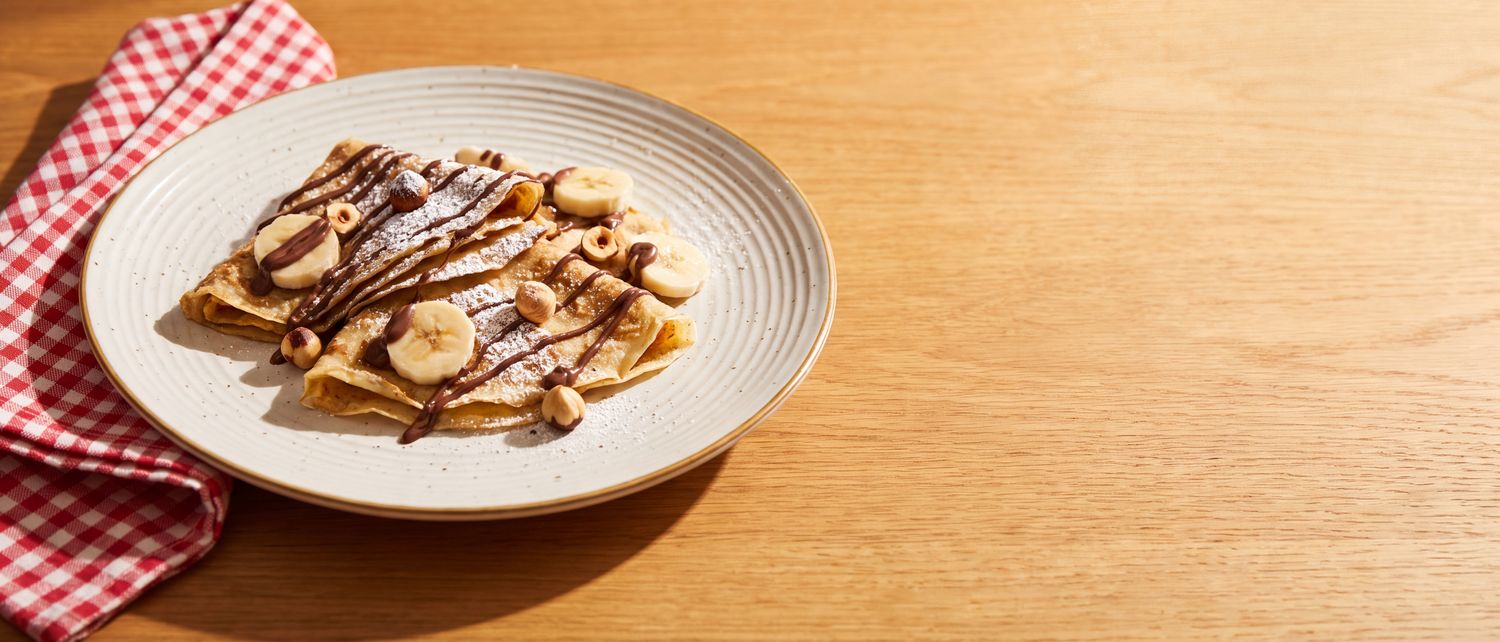 Folded crêpes dusted with icing sugar and drizzled with chocolate