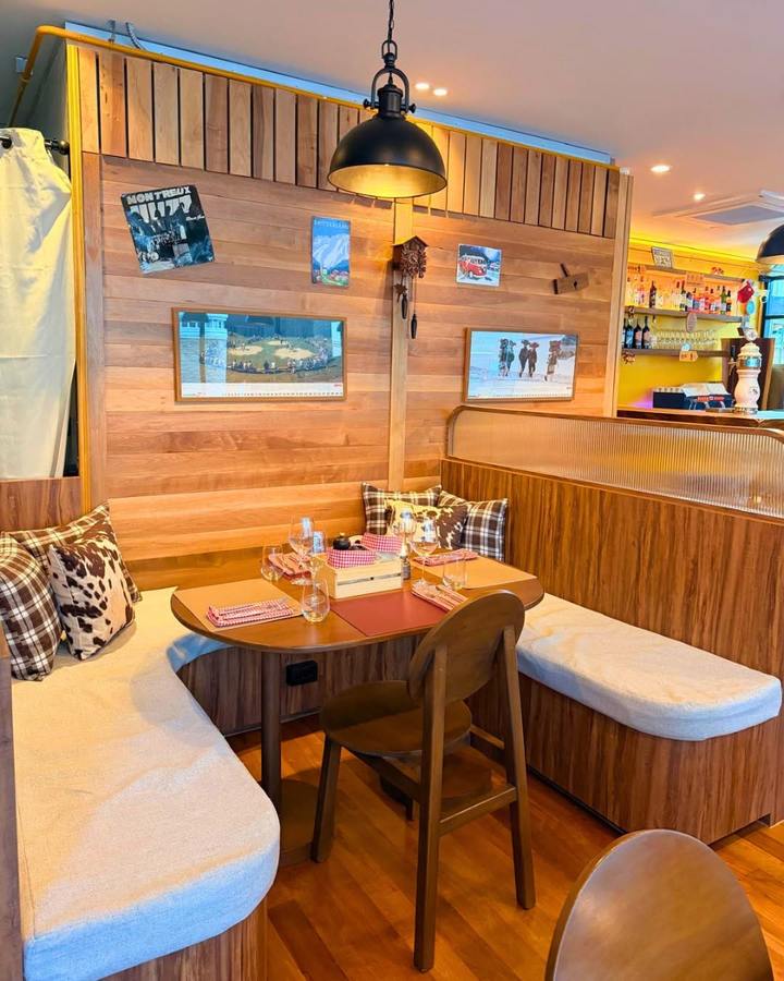 A corner booth with cow-print and check cushions against a pine wall